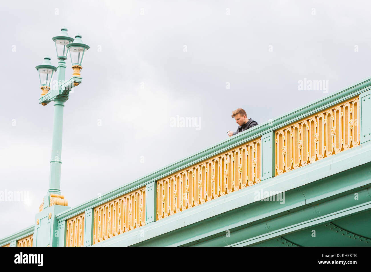 Londra, Regno Unito. Un giovane uomo guarda al suo telefono mobile a Southwark Bridge. Foto Stock