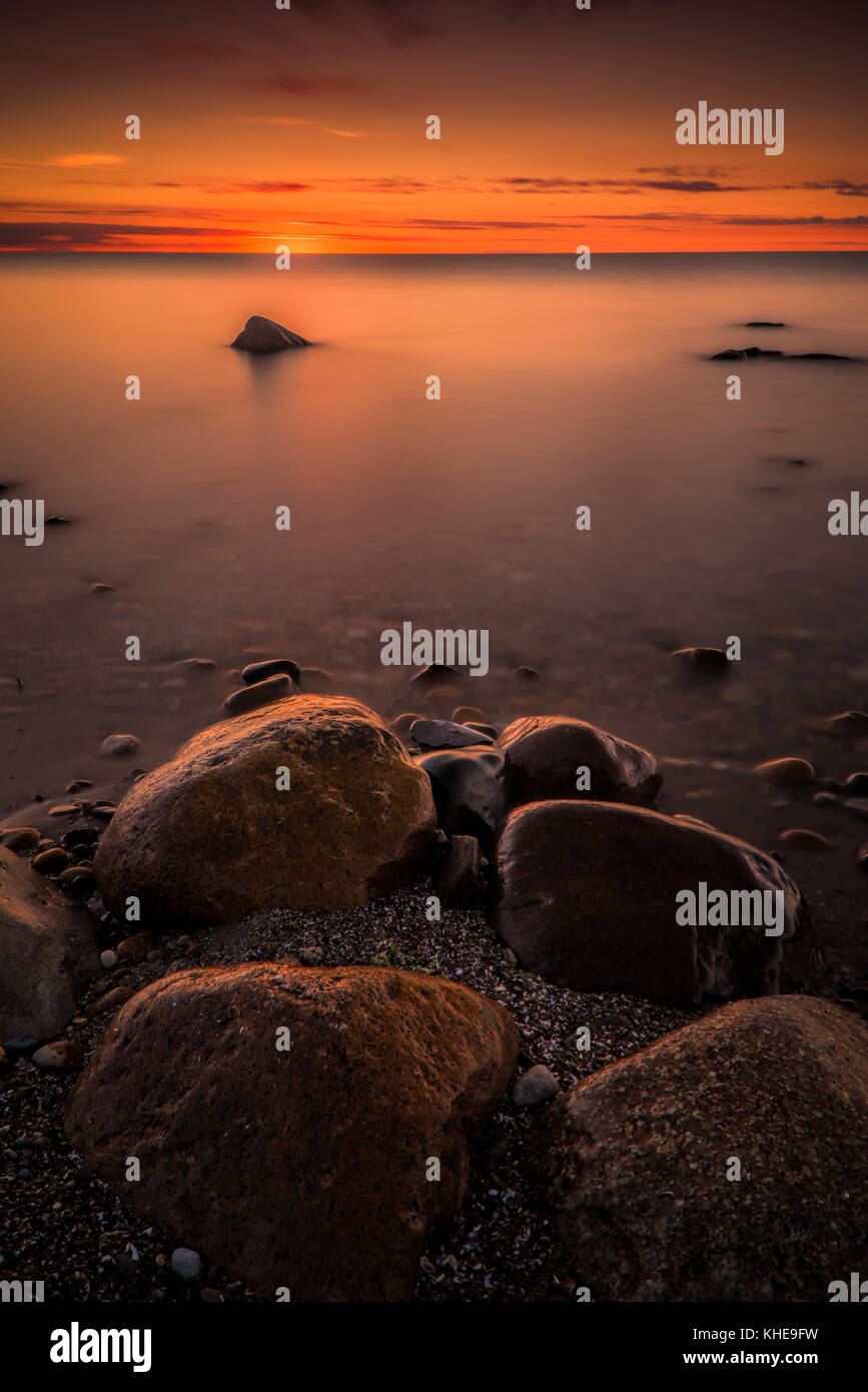 Twilight glow all'orizzonte su Lago Huron, Michigan con grande spiaggia di rocce, Stati Uniti, Nord America orientale Foto Stock