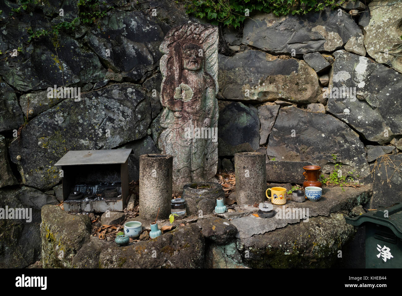 Nara, Giappone - 31 maggio 2017: Vecchia scultura in pietra onorata con tazze d'acqua e incenso nella foresta primordiale di Kasugayama Foto Stock
