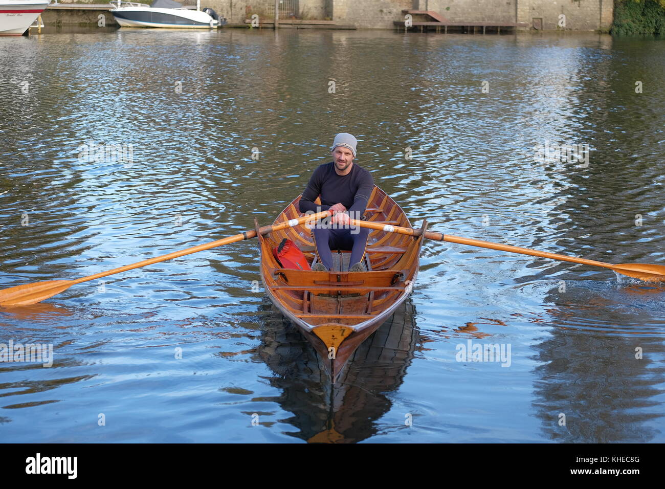 Uomo di canottaggio skiff di legno barca sul fiume Tamigi Foto Stock