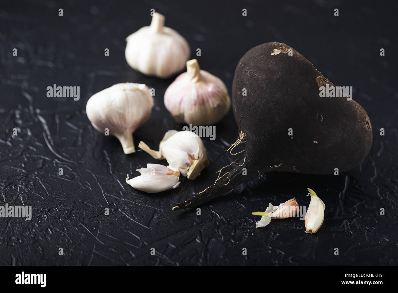 Il tubero Rafano nero e aglio su un nero lo sfondo di calcestruzzo Foto Stock