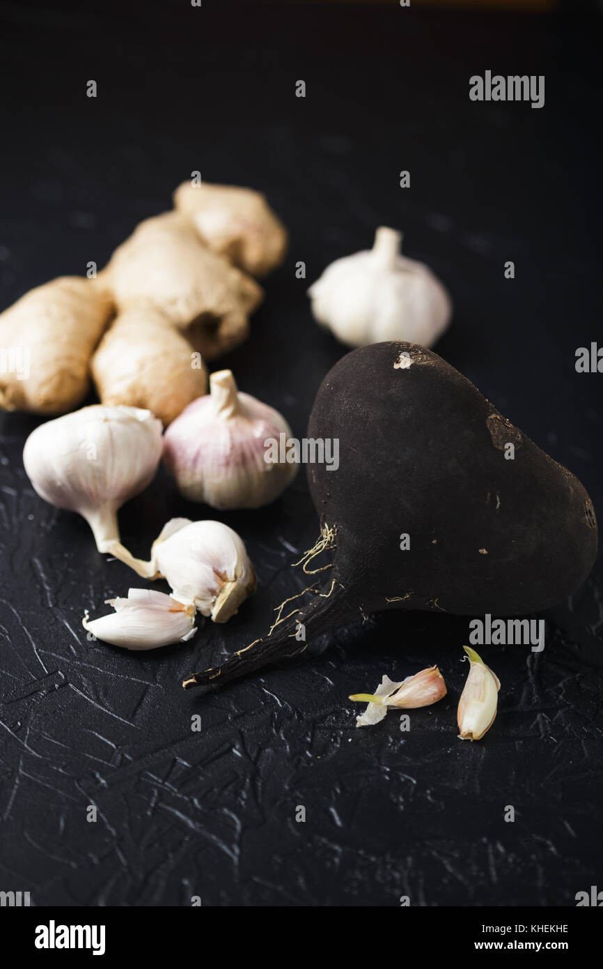 Il tubero Rafano nero e aglio su un nero lo sfondo di calcestruzzo Foto Stock