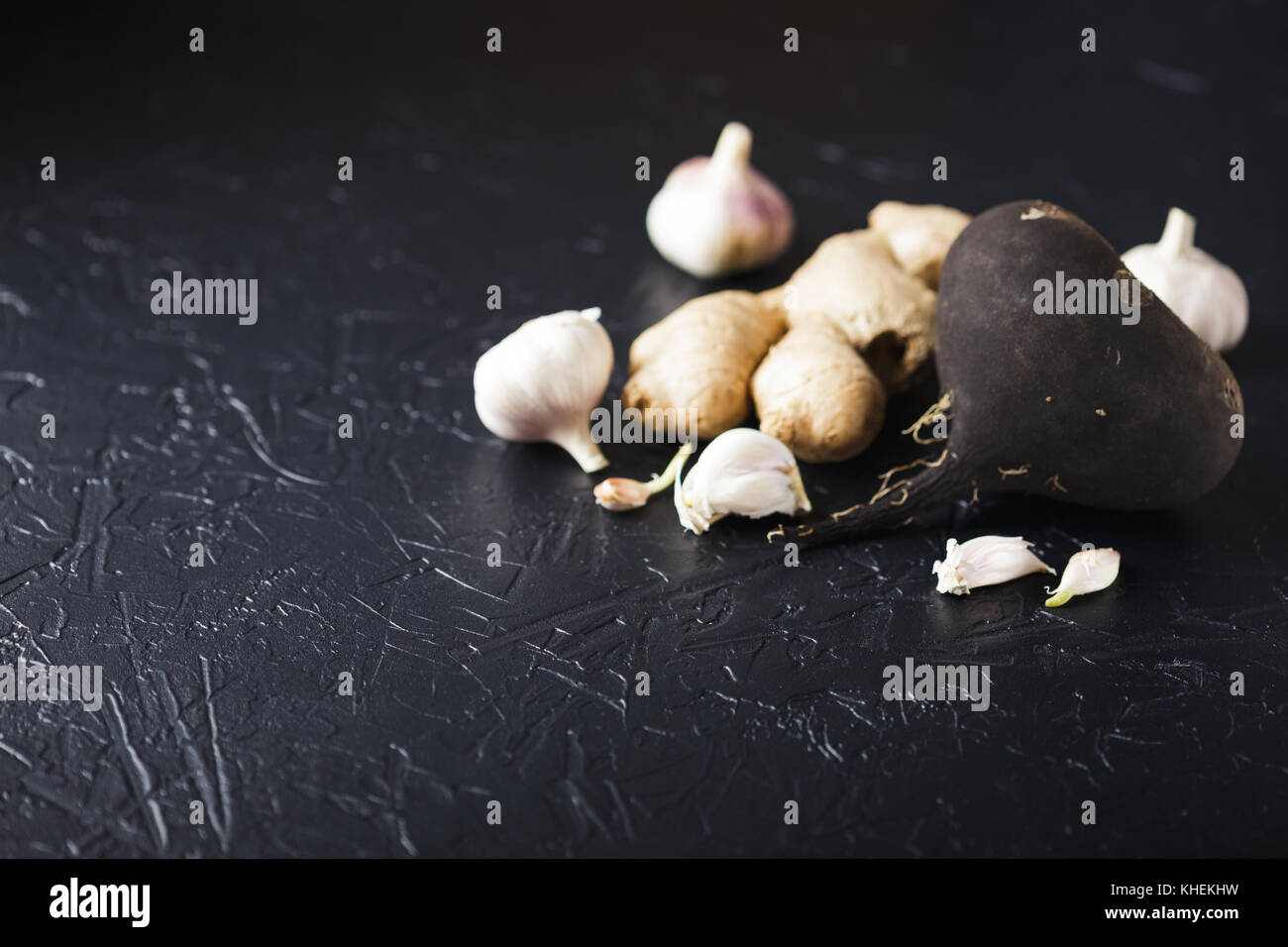 Il tubero Rafano nero e aglio su un nero lo sfondo di calcestruzzo Foto Stock