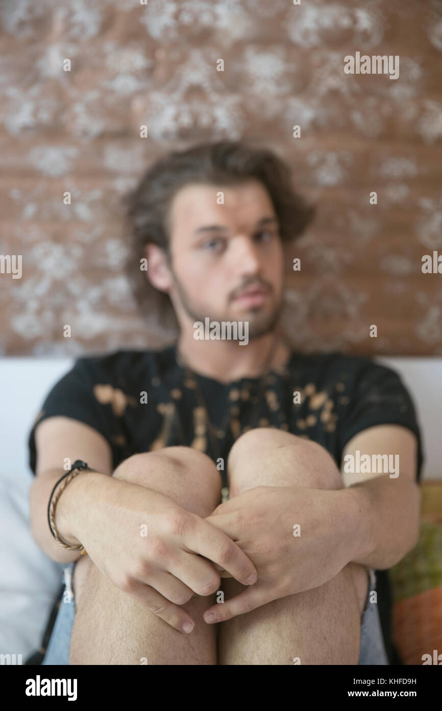 Giovane uomo seduto sul suo letto Foto Stock