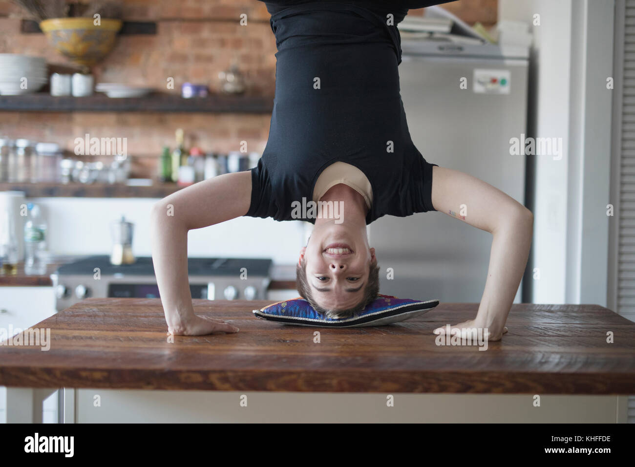 Transgender persona facendo un handstand sul loro banco di cucina Foto Stock
