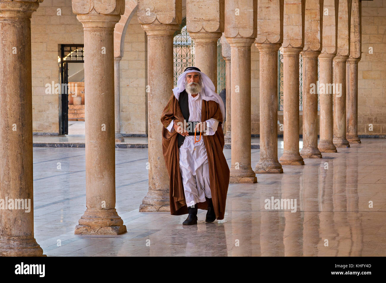 Uomo locale in abiti etnici camminando attraverso le colonne nel cortile della moschea Mevlidi Halil a Sanliurfa, Turchia. Foto Stock