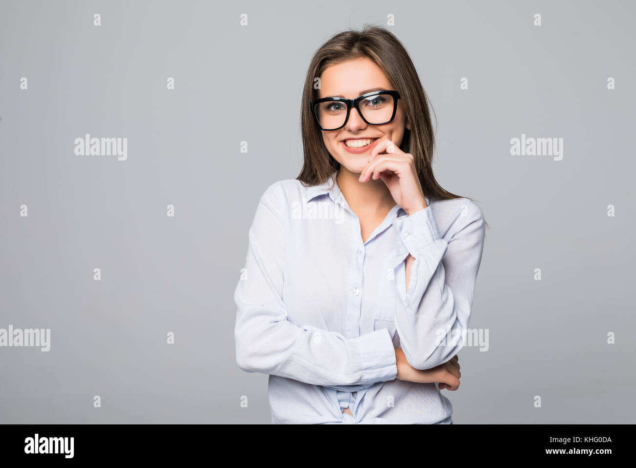 Brunette donna in bicchieri di pensare su sfondo grigio Foto Stock