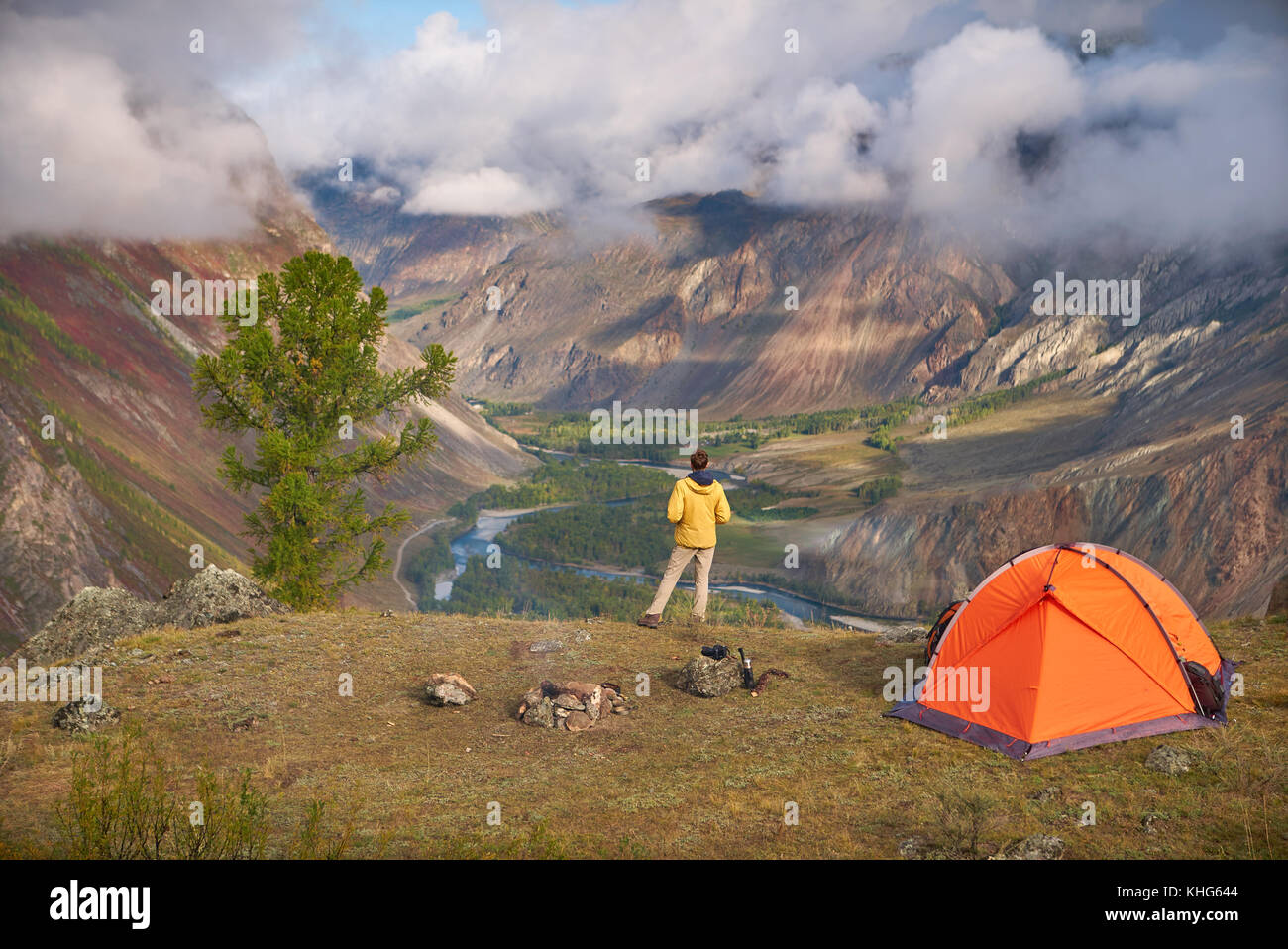 Persona che sorge nei pressi del campeggio e guardare la vista valle in cui vi è un fiume o di un ruscello e una foresta. il cielo è nuvoloso, ma il meteo è su Foto Stock