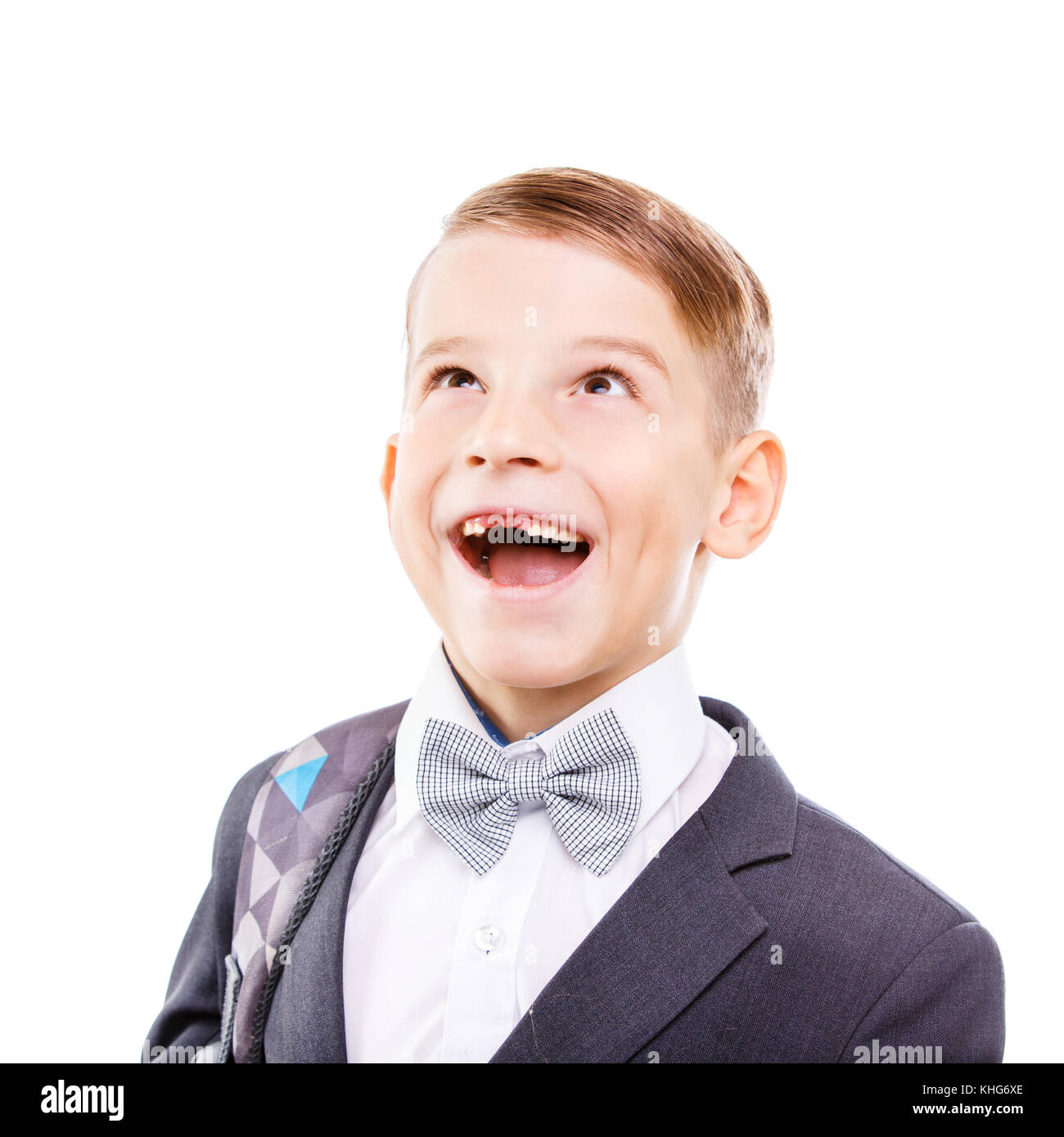 Scuola eccitato ragazzo con sorriso sdentati guardando in alto isolato su sfondo bianco Foto Stock