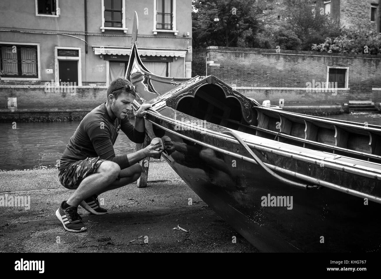Pulire una gondola e asciugarla prima del lavoro. Fotografare in un cantiere di barche in gondola, reportage fotografico in bianco e nero Foto Stock