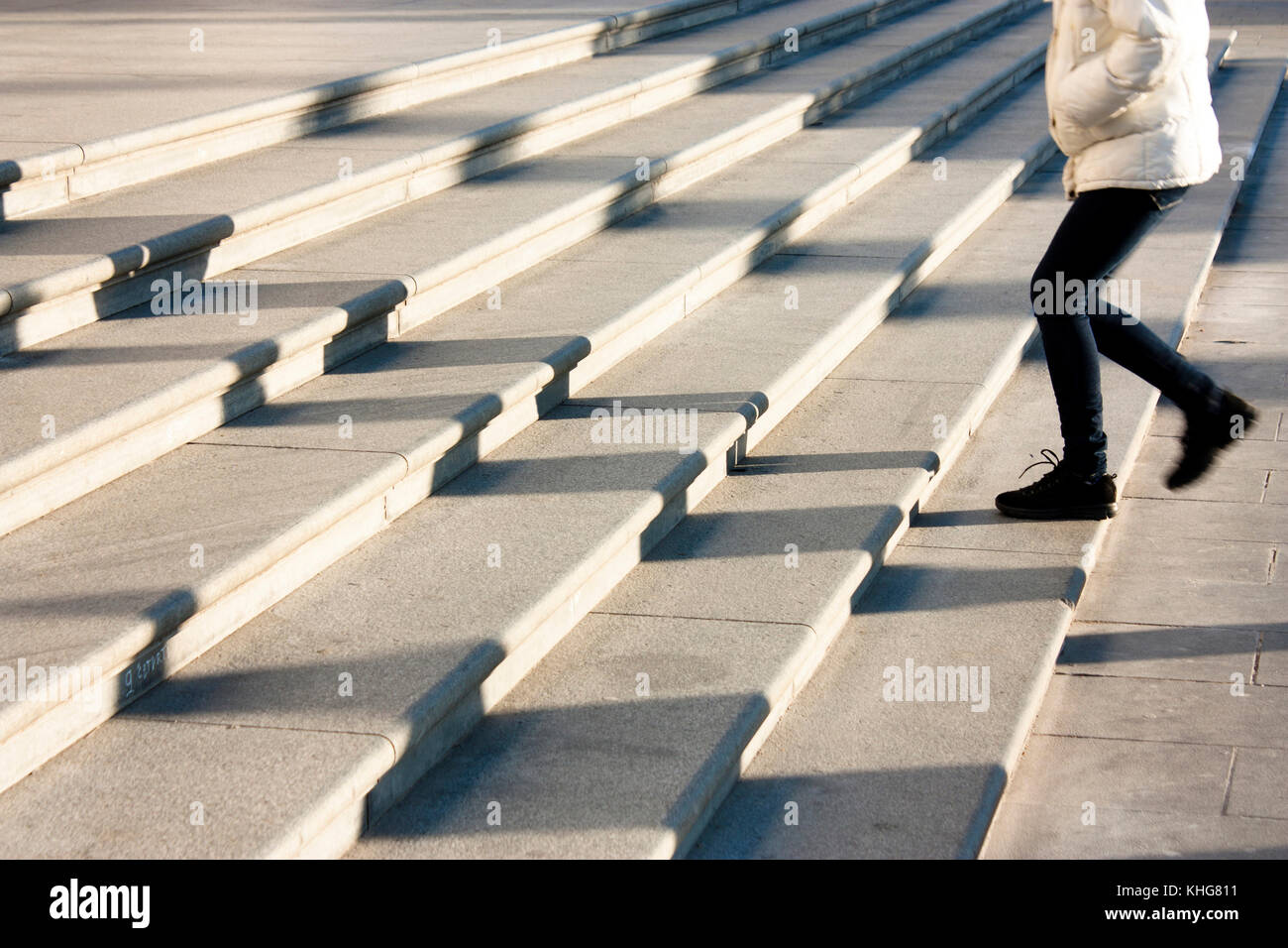 Una ragazza adolescente salendo le scale in motion blur e le ombre delle persone seguenti , sul pubblico enorme scalinata esterna Foto Stock
