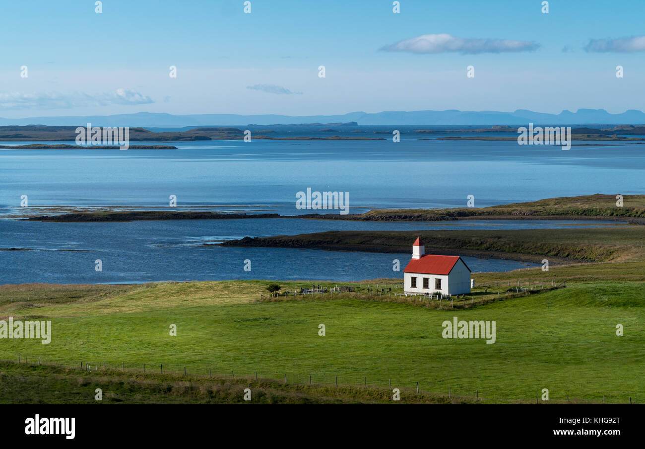 Piccola chiesa solitaria con un tetto rosso in Occidente l'Islanda con l'Westfjordsin sullo sfondo. Foto Stock