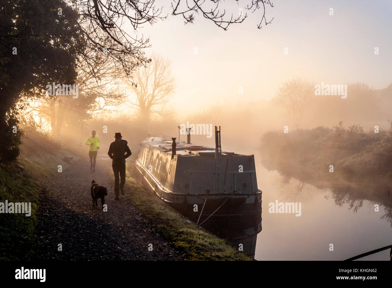 Bathampton, Somerset, Regno Unito meteo. 17 novembre 2017. Il sole sorge su narrowboats sul Kennet and Avon Canal su un gelido mattino luminoso. Per gli amanti del jogging e un dog walker sull'alzaia. Credito: Richard Wayman/Alamy Live News Foto Stock