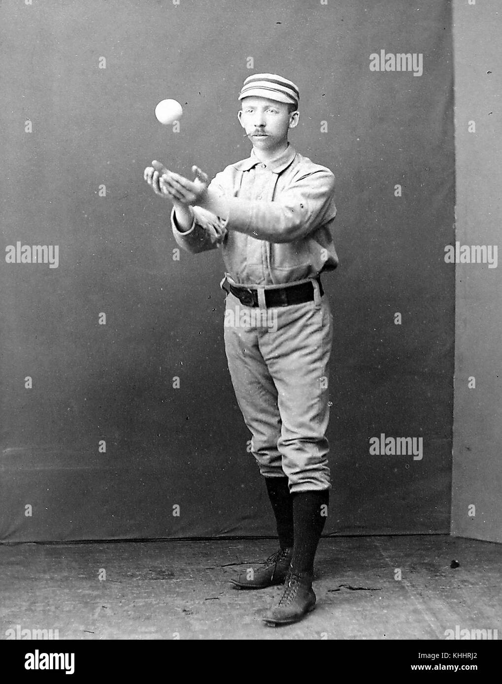 Un ritratto fotografico di Arthur Irwin che indossa un'uniforme dei Philadelphia Quakers, nella fotografia che si trova all'interno di uno studio e cattura una palla che gli è stata lanciata da qualcuno in piedi fuori dal telaio della telecamera, ha giocato a baseball della Major League per undici anni principalmente come interbase, ha anche lavorato nella lega come manager, scout e arbitro più tardi nella sua carriera, 1885. Dalla New York Public Library. Foto Stock