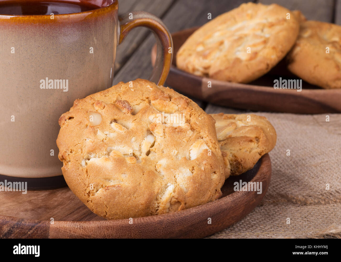 Primo piano di bianco dolci di cioccolato con nocciole di macadamia e tazza di caffè Foto Stock