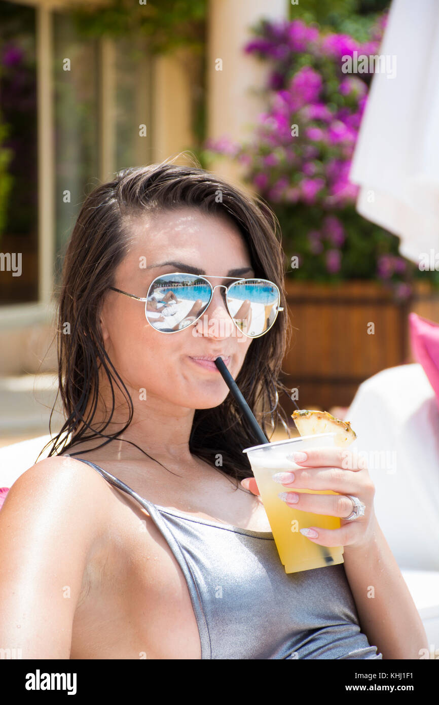 Bella donna che indossa un bikini bere bevande fredde in piscina Foto Stock