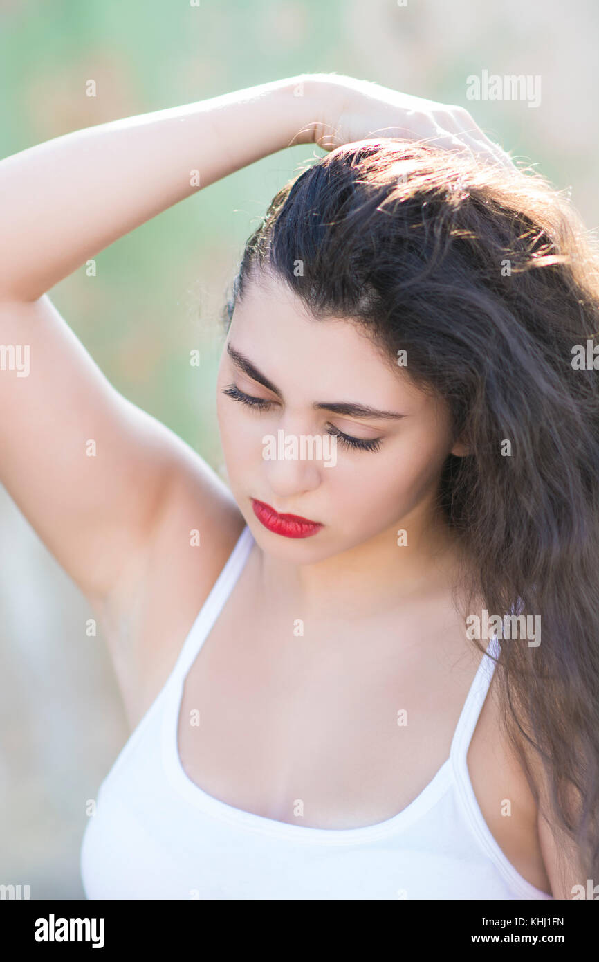 Bella giovane donna libanese mano sui capelli guardando verso il basso Foto Stock