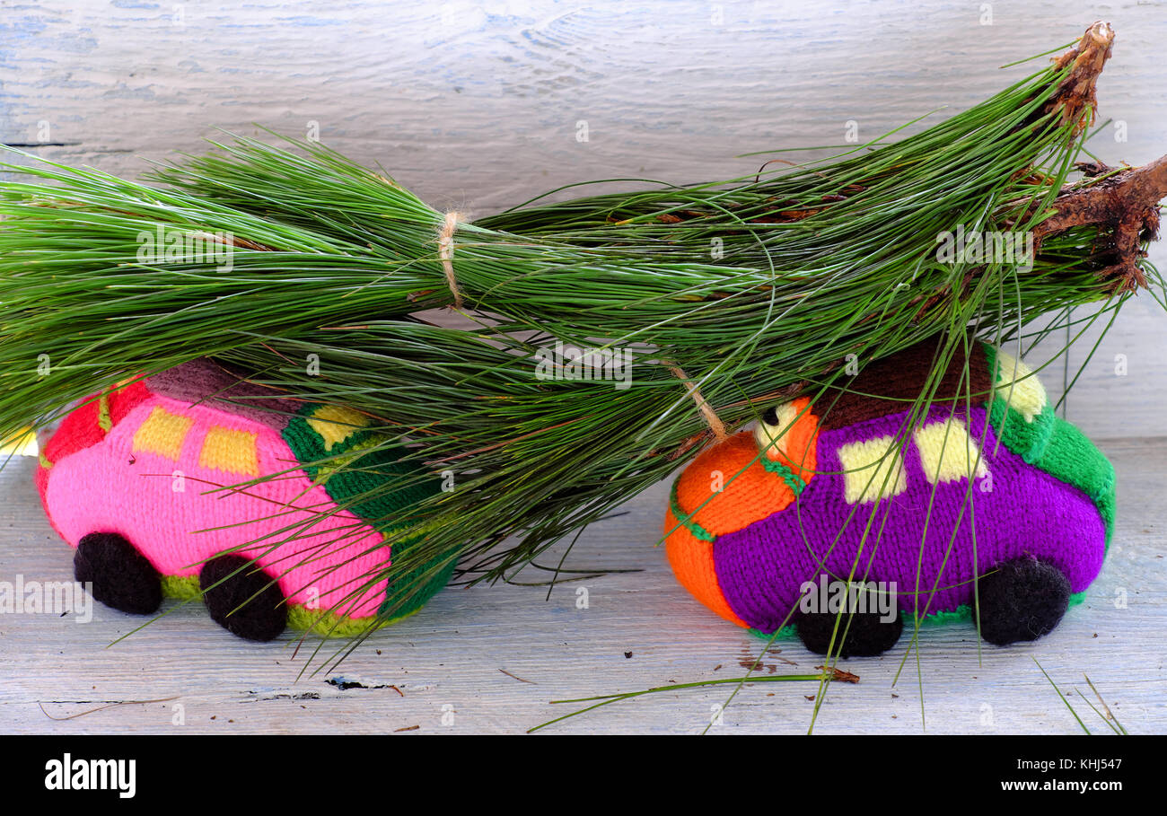Due auto trasporti pino per natale decorazione, maglia auto colorate si muovono su legno rendono divertente lo sfondo di Natale Foto Stock