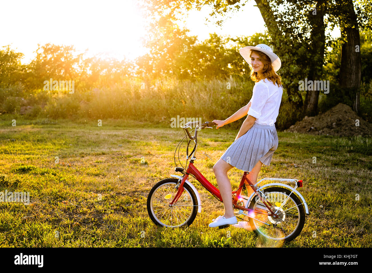 Bellissima giovane donna caucasica seduto su una bicicletta nel parco di estate giornata di sole Foto Stock