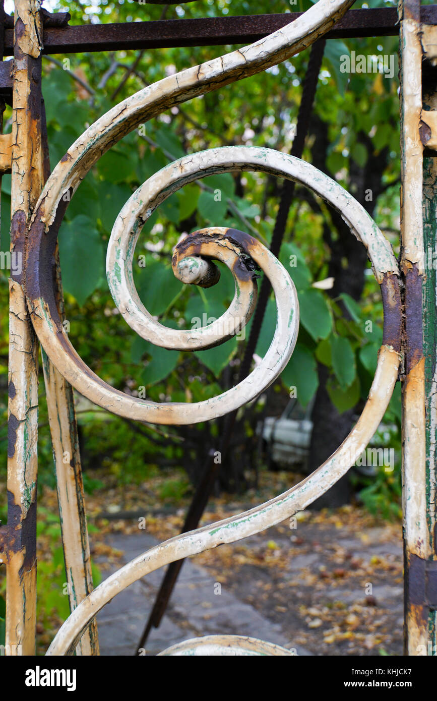Rusty decorazioni a spirale su un vecchio trascurato ornamentali recinzione in ferro Foto Stock