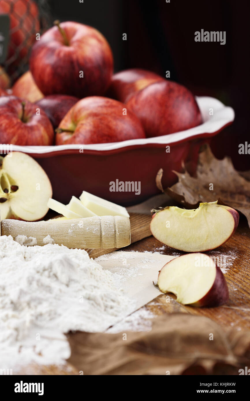 In legno antico mattarello spolverata di farina bianca su un tavolo rustico. apple ingredienti torta di mele e burro in background. extreme shallow dept Foto Stock