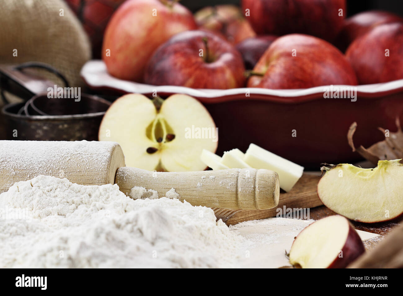 In legno antico mattarello spolverata di farina bianca su un tavolo rustico. apple ingredienti torta di mele e burro in background. extreme shallow dept Foto Stock