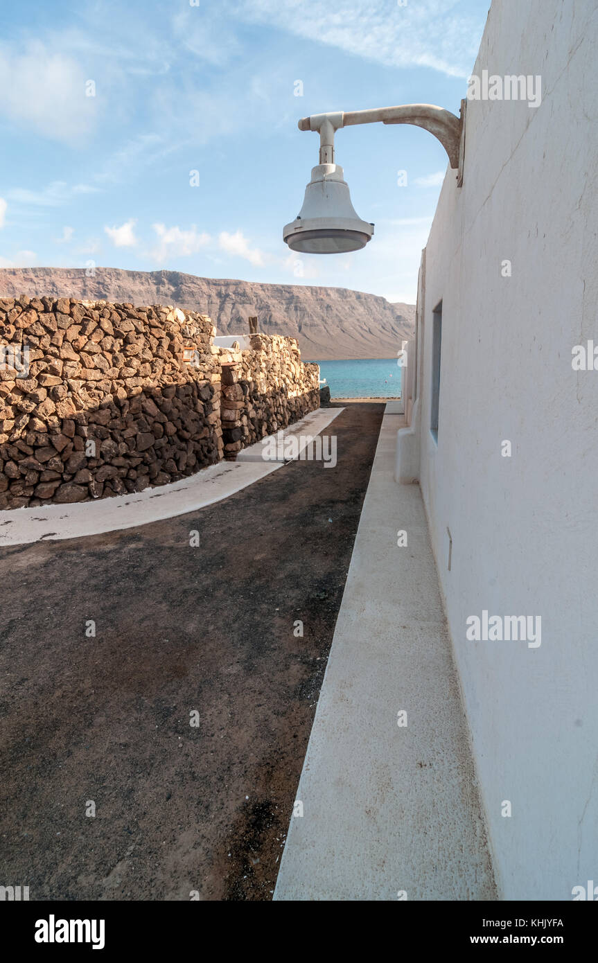 In prospettiva di una tipica strada con una via la luce in primo piano e la spiaggia in backround, Graciosa, Isole Canarie, Spagna Foto Stock