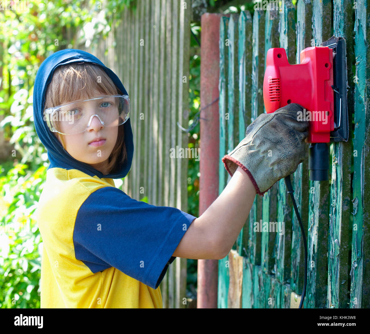 Ragazzo in occhiali protettivi macinazione di legno all'esterno. Foto Stock