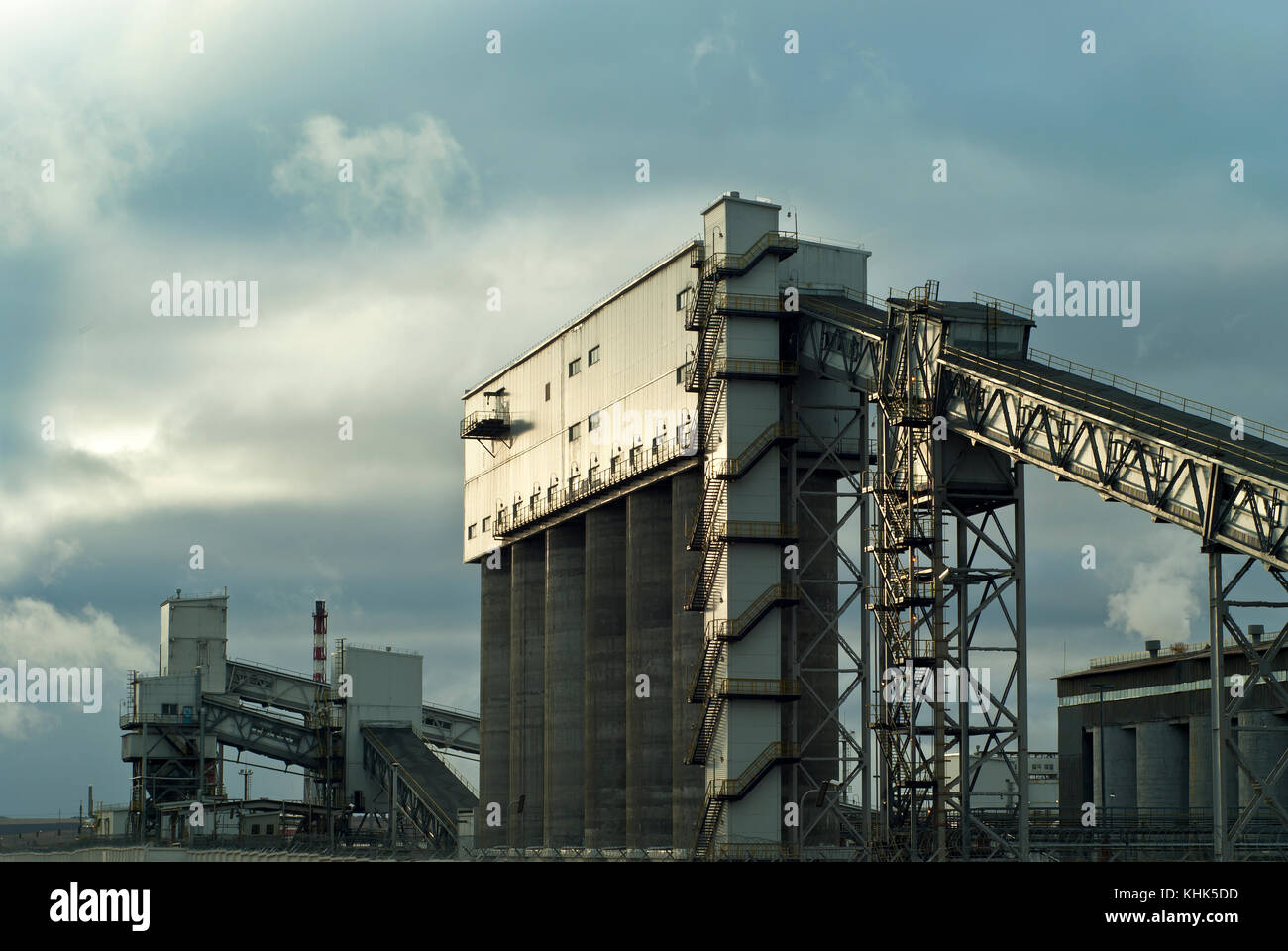 Un frammento di una moderna impresa industriale con diversi silos per lo stoccaggio di materiali sfusi e una coperta inclinata trasportatori a nastro Foto Stock