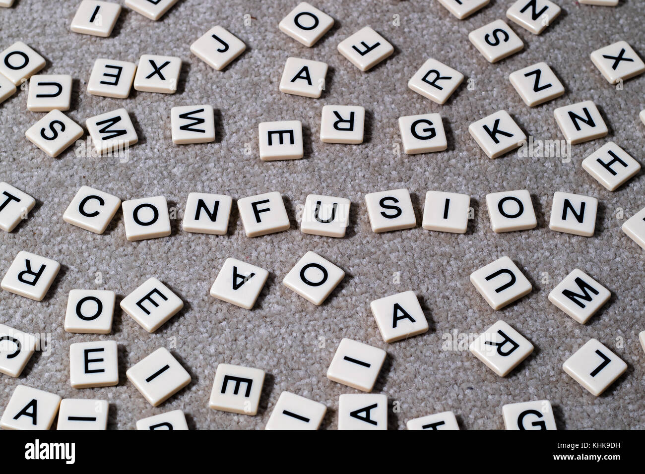Confusione enunciato in stile scrabble letterati piastrelle tra una ridda di altre lettere. Foto Stock