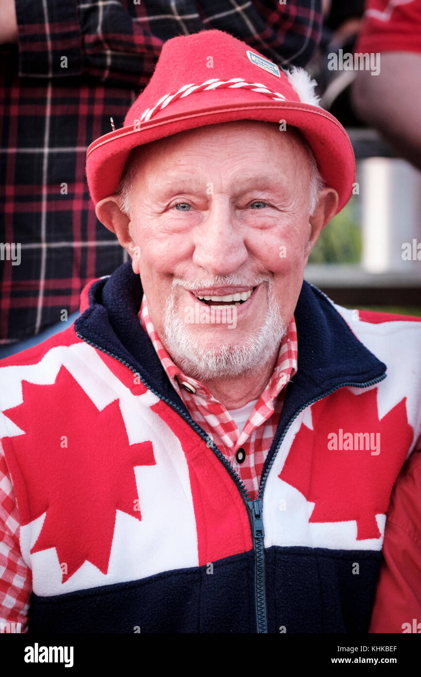 Ritratto di un cittadino anziano patriottico canadese che celebra il Canada Day indossando un cappello, colori nazionali rosso e bianco, sorridente alla macchina fotografica. Foto Stock
