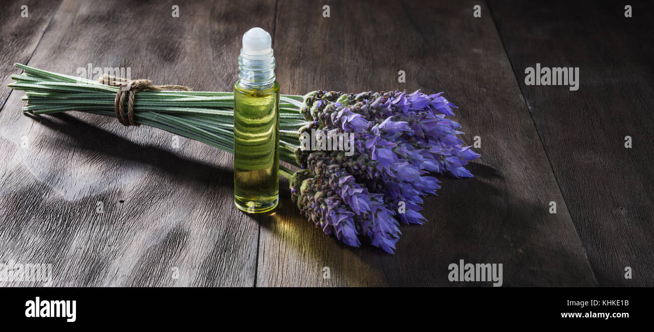 Freschi di fiori di lavanda e olio essenziale come aromaterapia naturale per il mal di testa ed emicrania di rilievo sul vecchio sfondo di legno Foto Stock