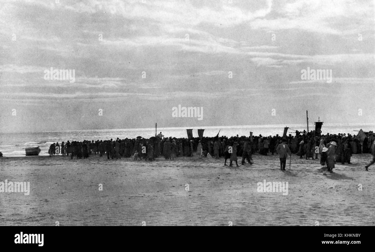 Una fotografia raffigurante un gruppo di contadini che marciavano verso il mare portando striscioni, lo facevano due volte l'anno per benedire il mare per aver dato loro Mary Salome, Mary Jacobe, Maria Maddalena che, secondo la tradizione locale, salpò dall'Egitto dopo la crocifissione di Gesù e vi sbarcò, Saintes Maries de la Mer, Camargue, Francia, luglio 1922. Foto Stock
