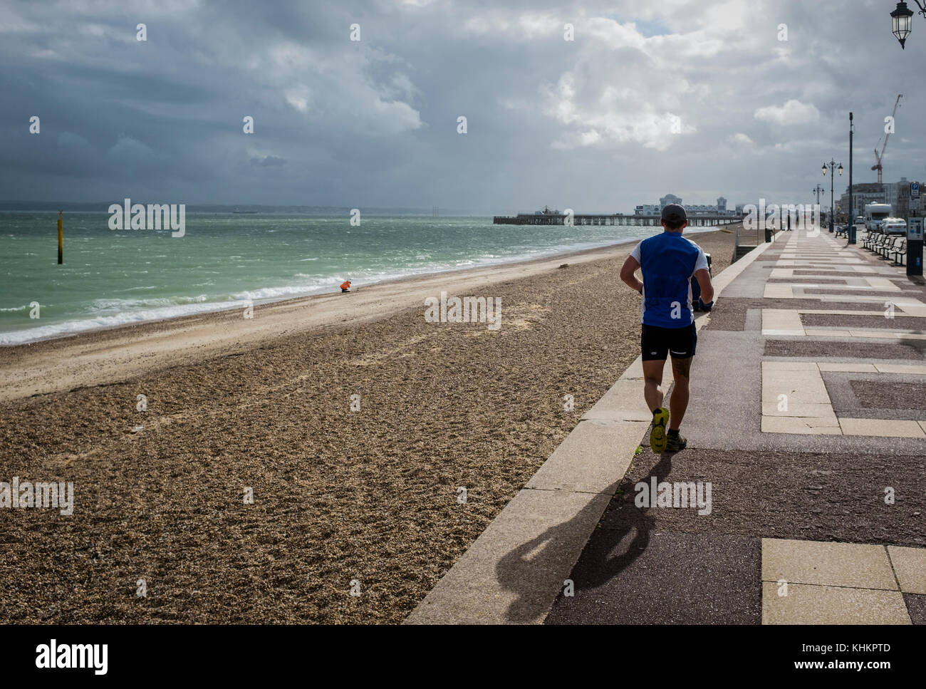 South Parade a Southsea con un jogger che corre verso il molo South Parade in condizioni meteorologiche drammatiche. Vista posteriore. Foto Stock