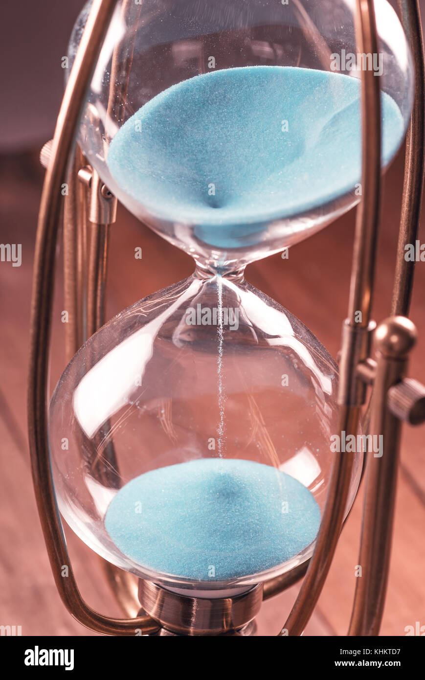 Clessidra con sabbia in colore blu e corpo in vetro bloccato dal telaio metallico. Foto Stock