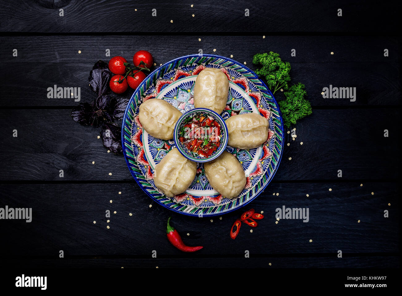 Al vapore tradizionale gnocchi manti sulla piastra con oriental ornamento con salsa di pomodoro. vista dall'alto. in legno scuro dello sfondo. Foto Stock