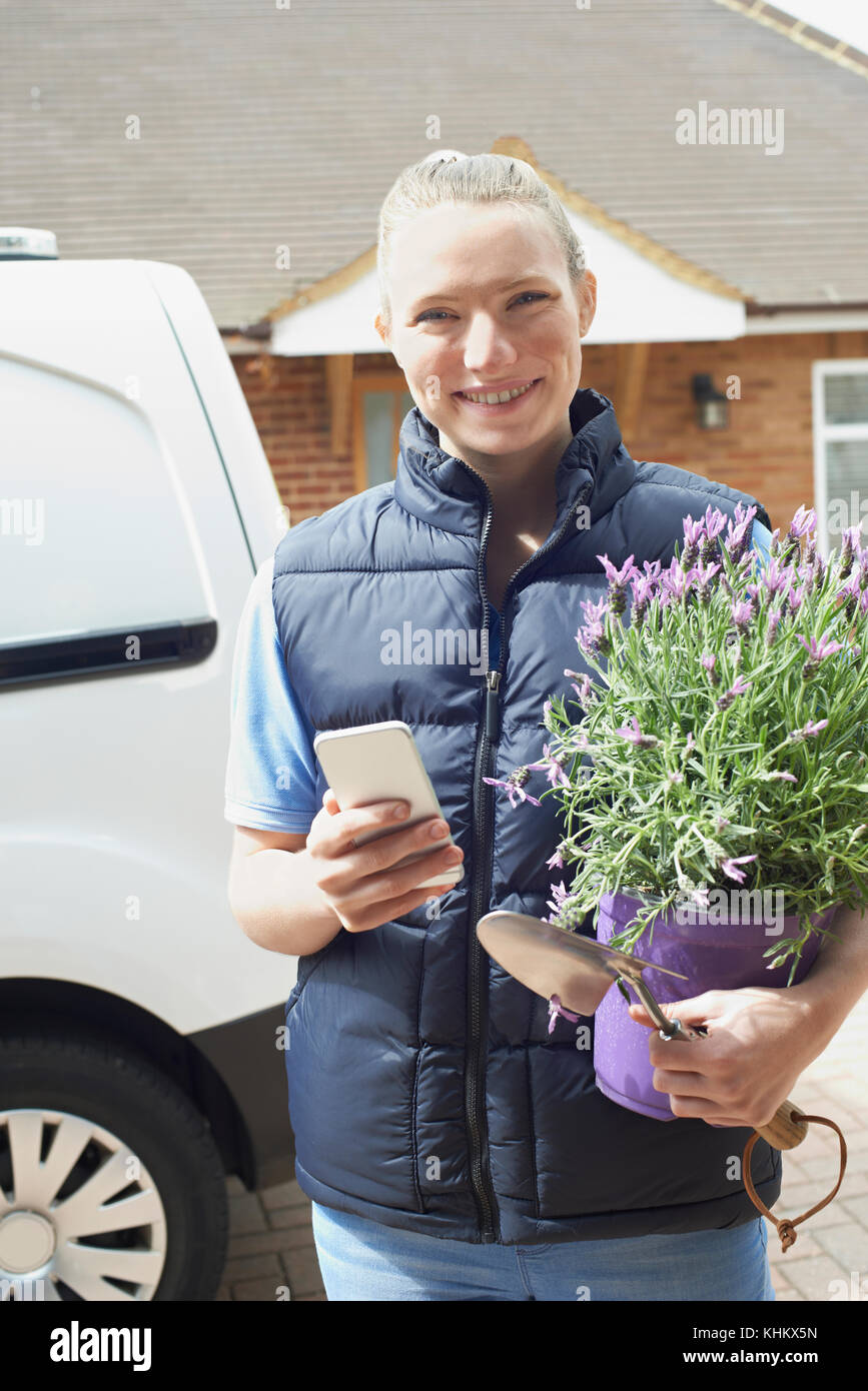 La donna in esecuzione il giardinaggio mobile business utilizzando il telefono cellulare Foto Stock