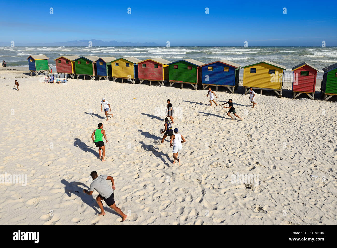I ragazzi giocare a rugby in parte anteriore di colorate case sulla spiaggia, muizenberg false bay, Western Cape, Sud Africa Foto Stock