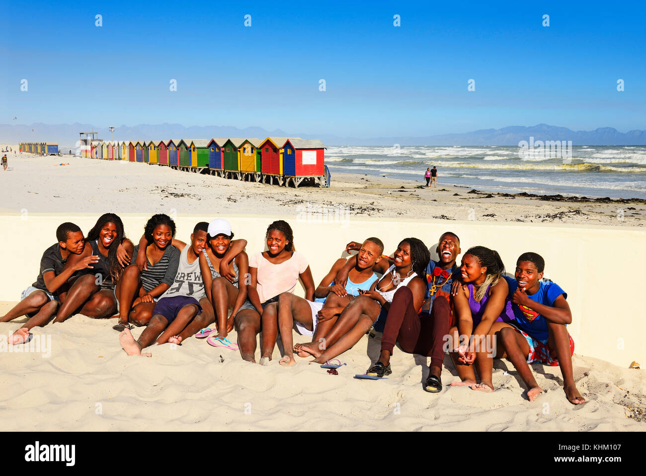 Felice nero adolescenti sulla spiaggia, colorato beach cottages, muizenberg false bay, Western Cape, Sud Africa Foto Stock