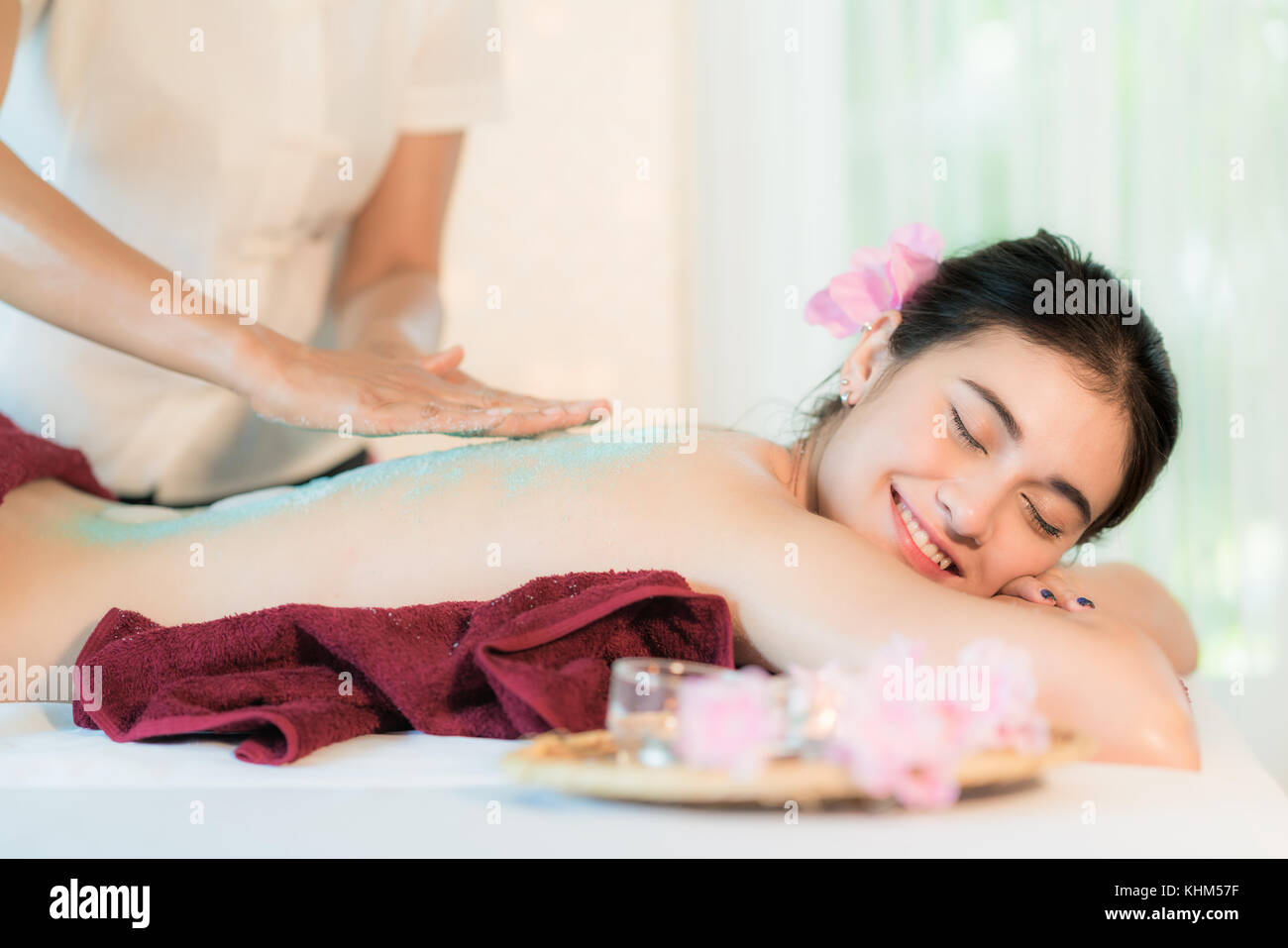 Giovane donna asiatica la ricezione sale massaggio nella spa salone, mettendo mano scrub al sale sul retro femmina, spa concept Foto Stock