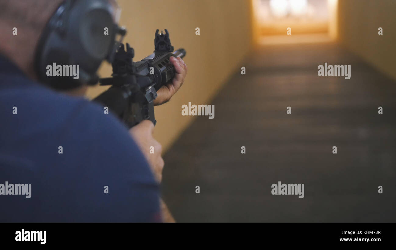 L'uomo istruttore sono riprese con un machinegun ha in galleria di tiro Foto Stock