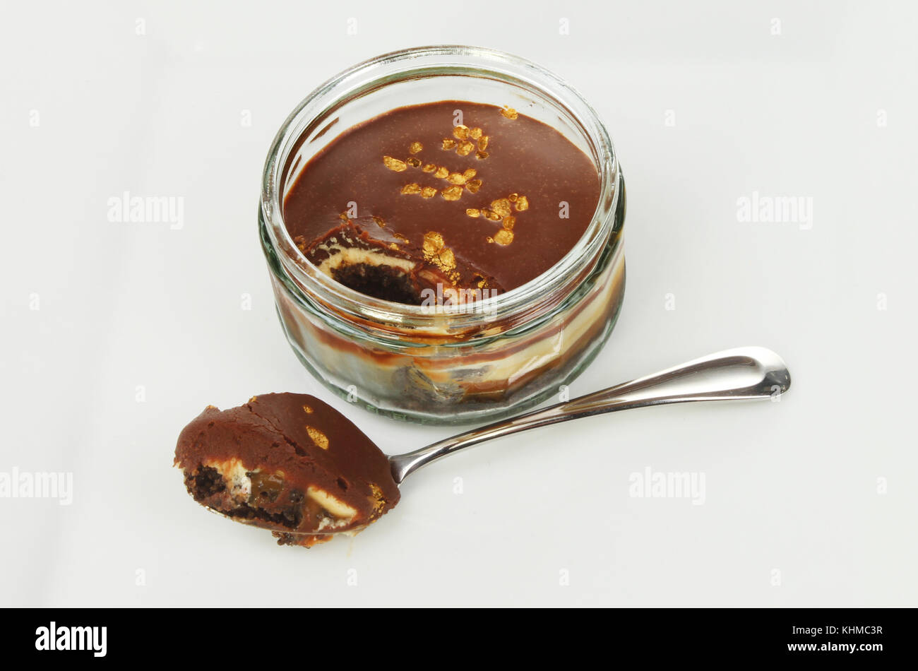Cheesecake al cioccolato in un vasetto con un cucchiaio su una piastra Foto Stock