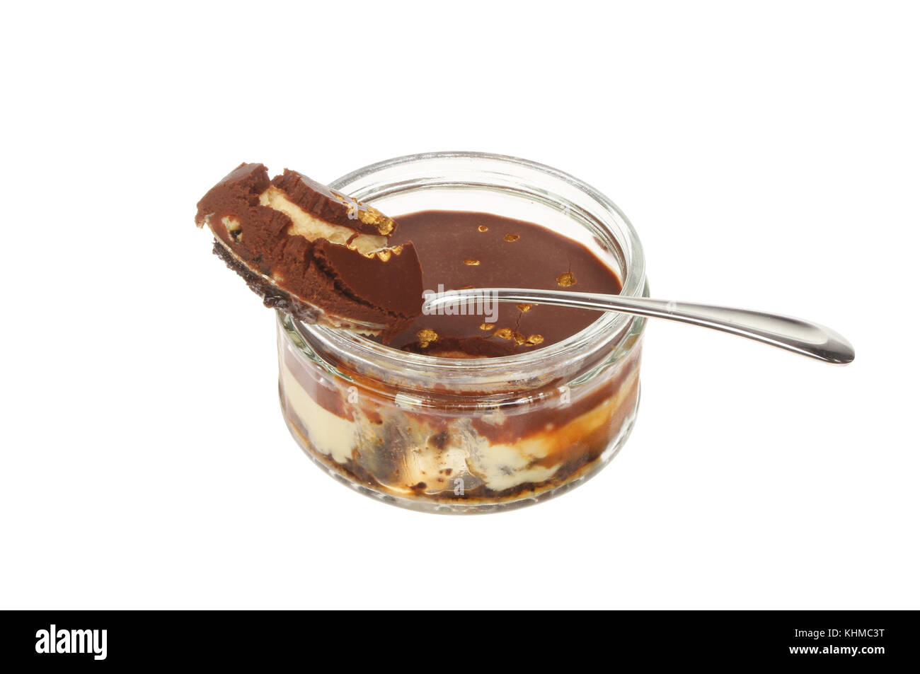 Cheesecake al cioccolato in un vaso con una porzione in un cucchiaio isolata contro bianco Foto Stock