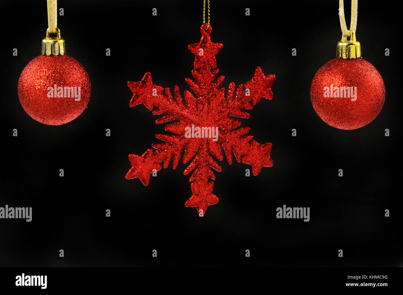 Red glitter baubles di natale e il simbolo del fiocco di neve stella isolata contro il nero Foto Stock