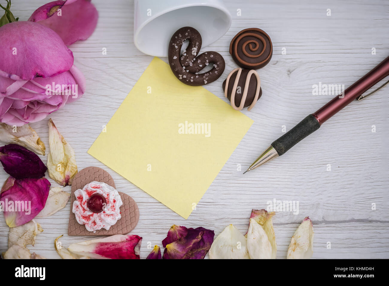 Rosa rosa, chcolate, petali e una matita su sfondo bianco Foto Stock