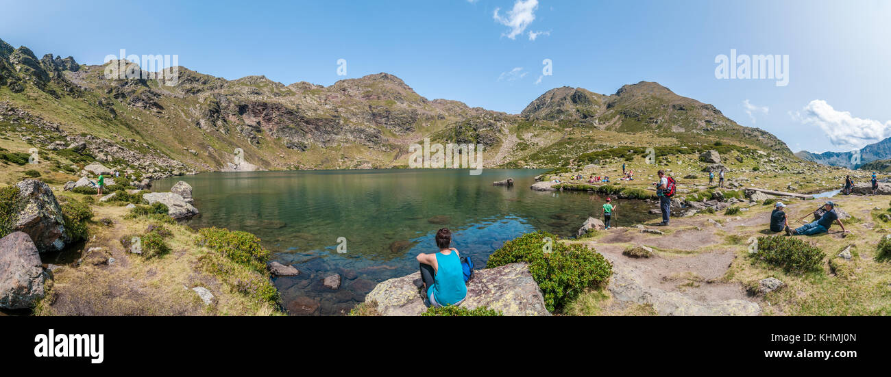 Vista panoramica del lago di alta montagna chiamato 'Estany de més amunt' vicino a Ordino con alcune persone escursionismo e a riposo Tristaina, Andorra Foto Stock