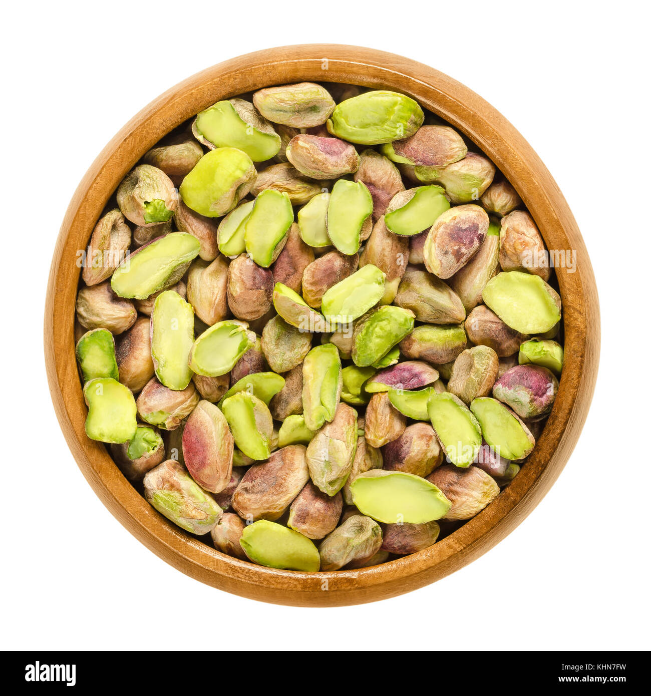 Pistacchio sgusciato kernels nella ciotola di legno. essiccati Sementi e frutti maturi di Pistacia vera. snack. isolato cibo macro foto da vicino da sopra il bianco. Foto Stock