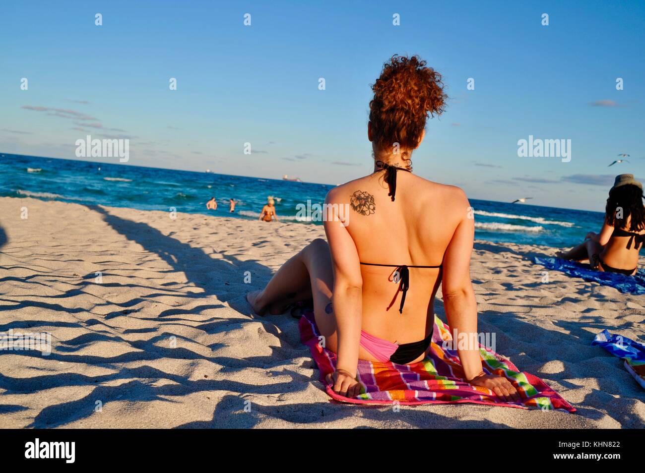 Belle Donne bagni di sole sulla spiaggia nel tardo pomeriggio a South Beach, Miami, Florida, Stati Uniti d'America. Foto Stock