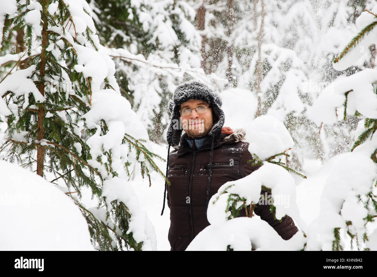 Uomo in pelliccia Cappello invernale con paraorecchi sorridente ritratto. extreme nella foresta Foto Stock