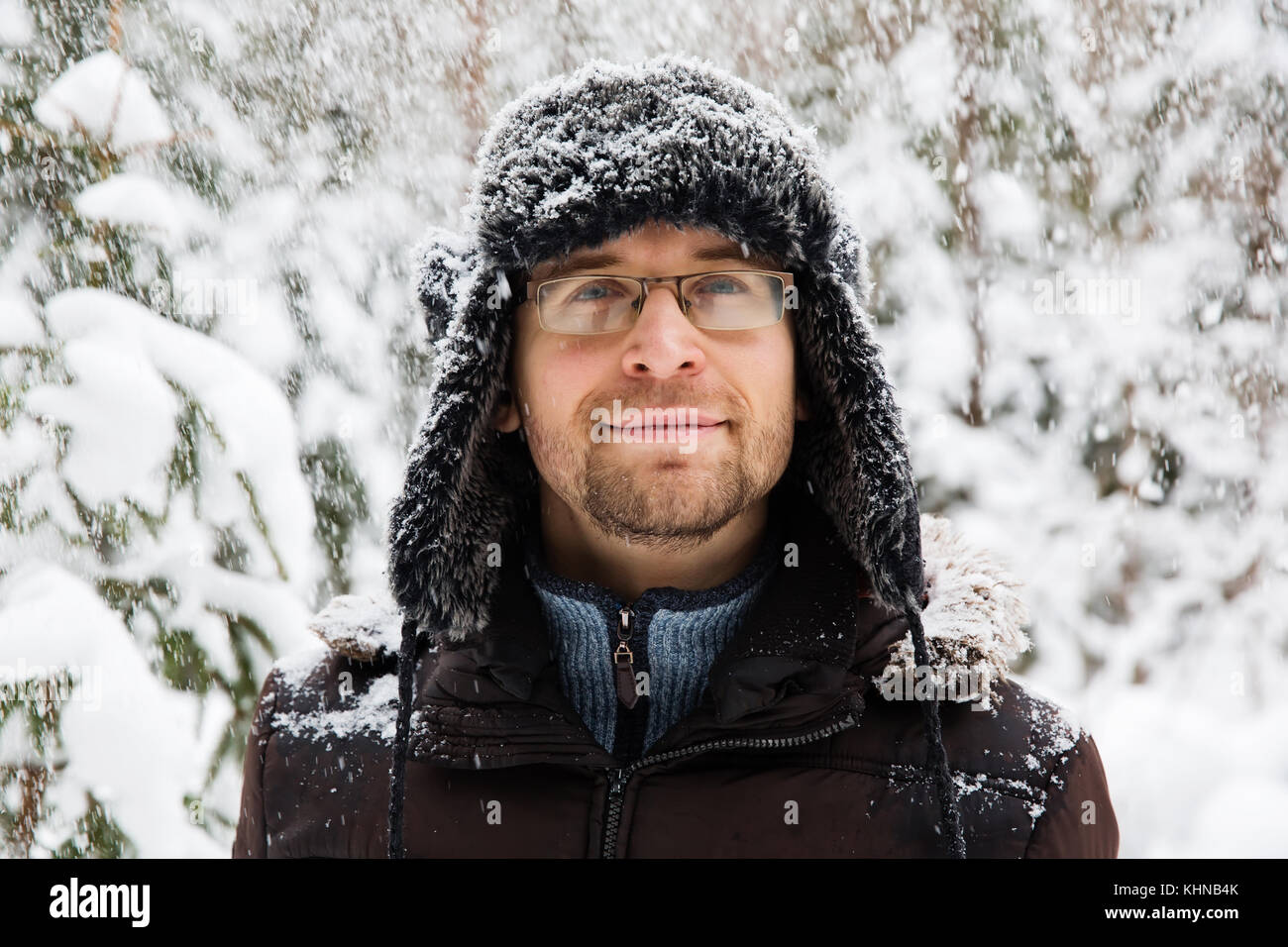 Uomo in pelliccia Cappello invernale con paraorecchi sorridente ritratto. extreme nella foresta Foto Stock